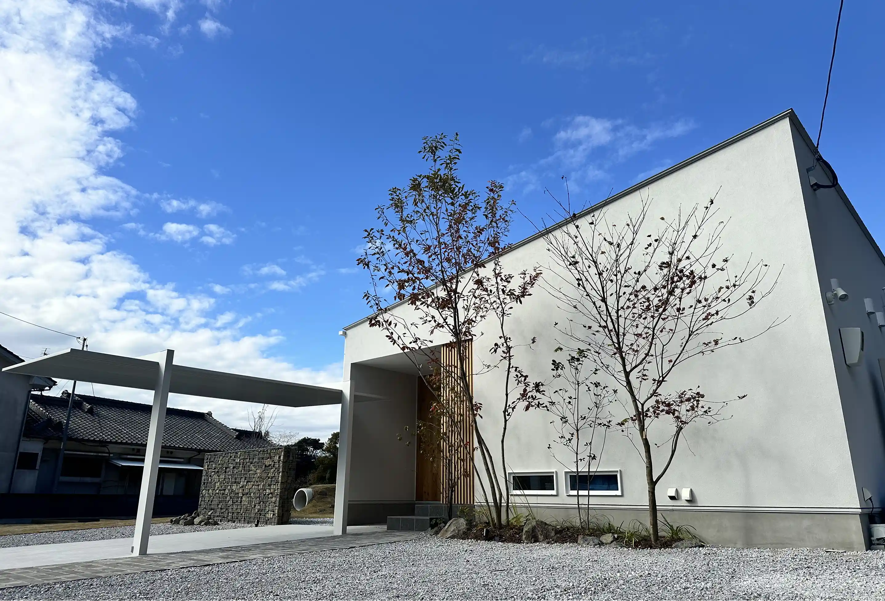 木製デッキと植栽が美しい外構デザイン。玄関前のスペースが整えられ、建物と調和した温かみのあるエントランス
