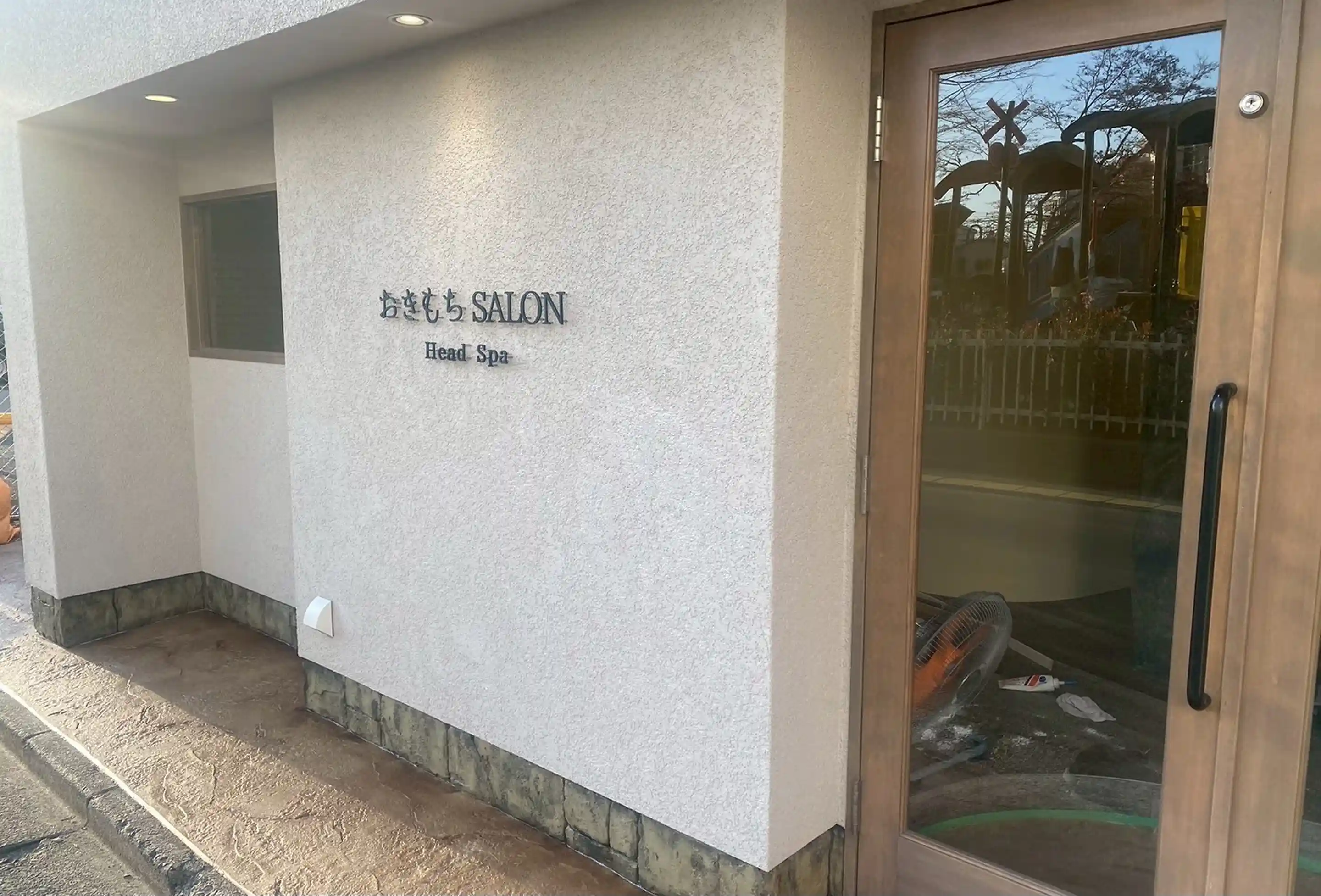 店舗外観のエントランス。ナチュラルな色味の外壁と木製ドアが印象的なデザイン